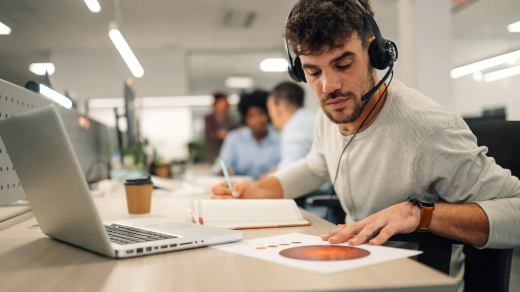 Offshore accounting professional reviewing financial reports at a laptop in an open-plan office